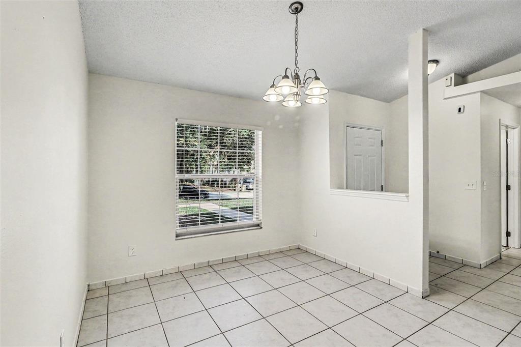 A dining area with white walls, tile flooring, a window, and a hanging light fixture — 10717 SIENA DRIVE, CLERMONT, FL