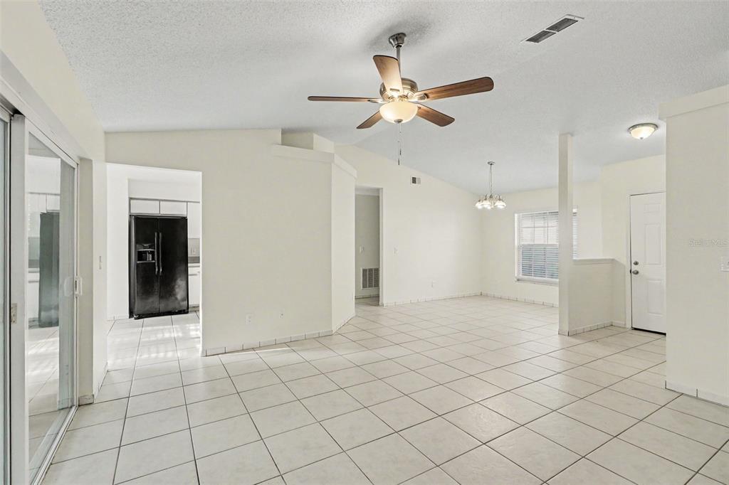 An open-concept living and dining area features white walls, tiled floors, and a ceiling fan — 10717 SIENA DRIVE, CLERMONT, FL