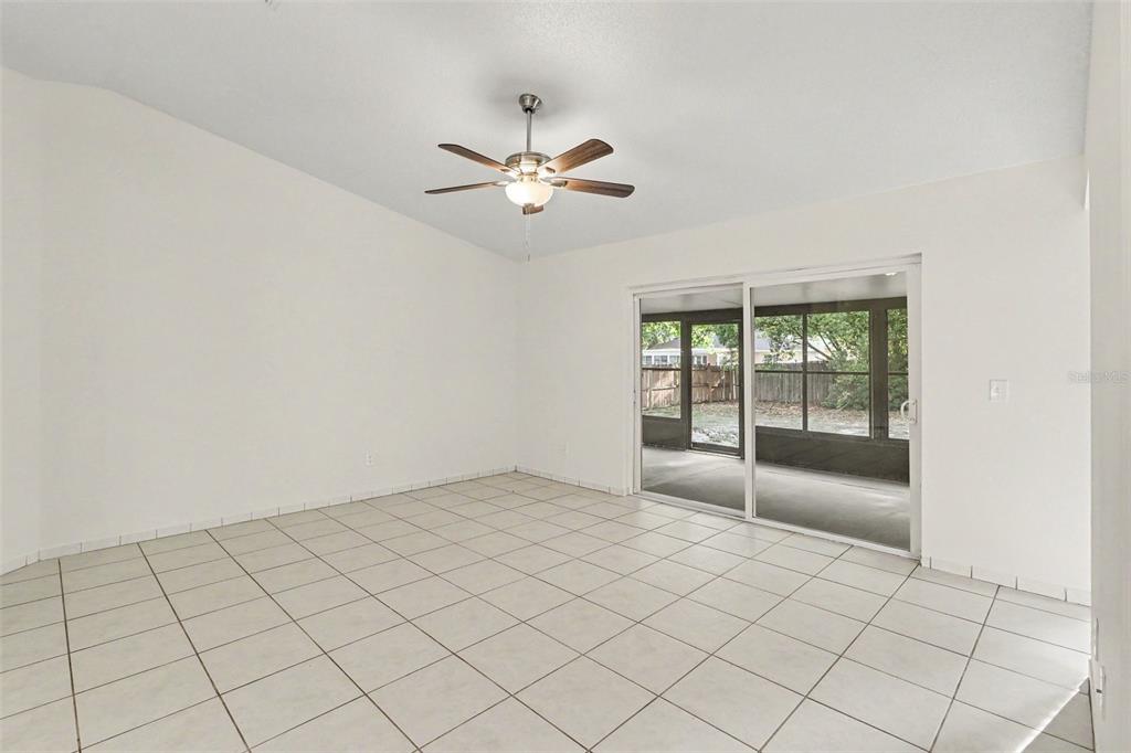 A room with white tile floors, a ceiling fan, and sliding glass doors to a patio — 10717 SIENA DRIVE, CLERMONT, FL