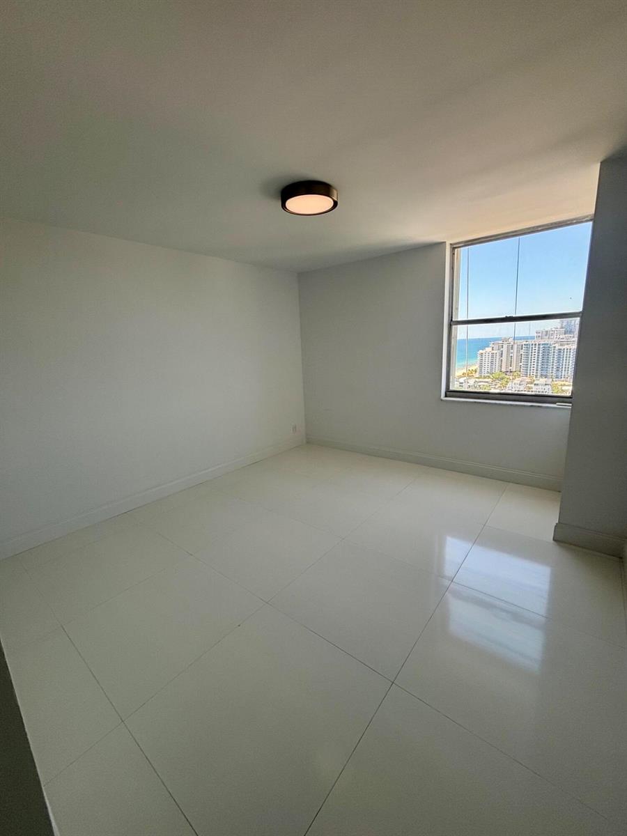 An empty room with white tile floors, a ceiling light, and a window overlooking buildings — 111 Briny Avenue # 14, Pompano Beach FL 33062, POMPANO BEACH, FL