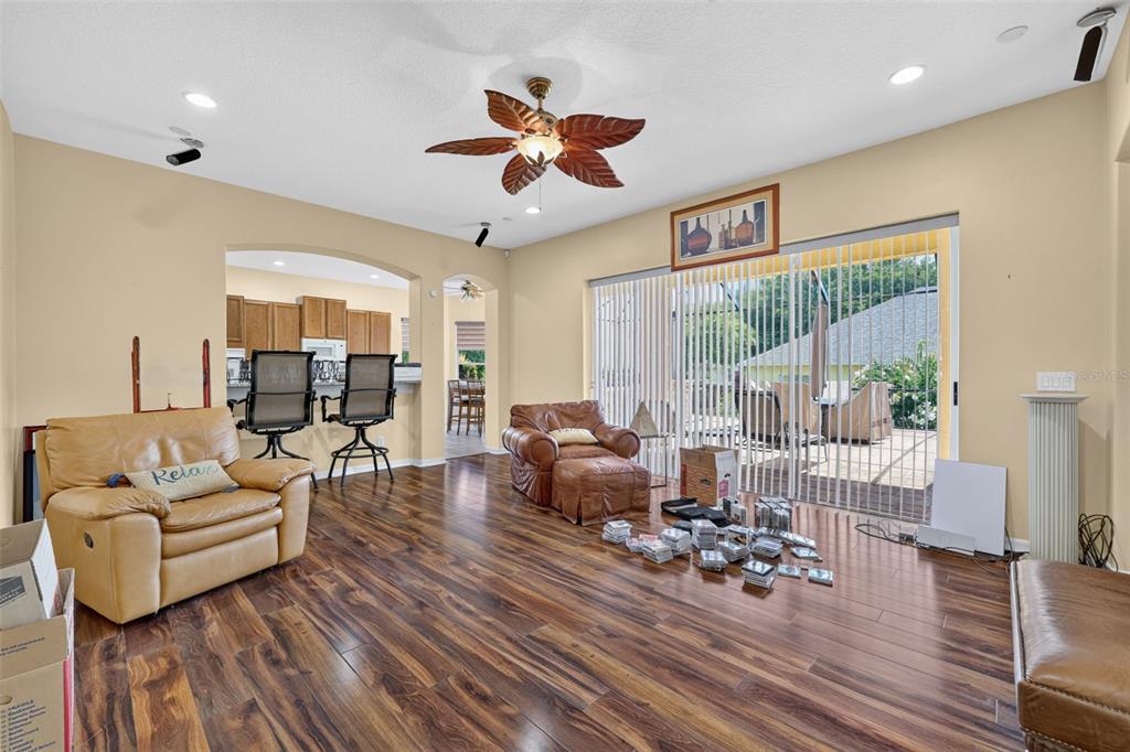 A living room with wood-look flooring, a ceiling fan, and sliding glass doors to a patio — 316 HARTS OAK PLACE, SEFFNER, FL