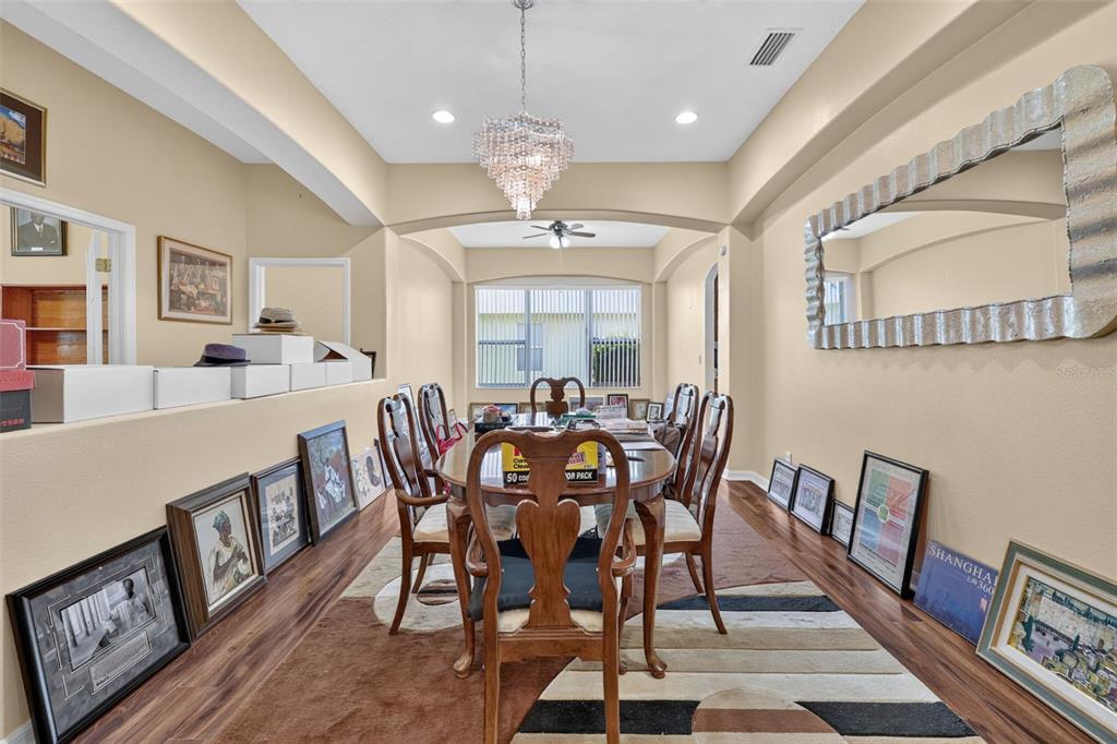 A dining room features a chandelier, a large mirror, and numerous framed pictures on the floor — 316 HARTS OAK PLACE, SEFFNER, FL