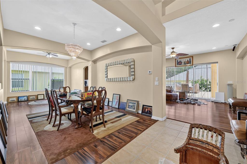 A dining area with a crystal chandelier, wood flooring, and an adjacent living room space — 316 HARTS OAK PLACE, SEFFNER, FL