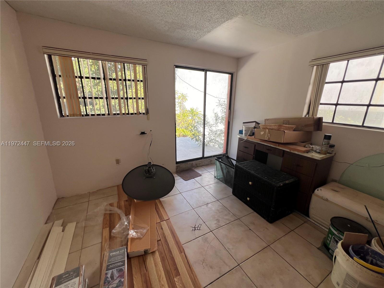 A room with tiled floors, two windows, a sliding glass door, and scattered construction materials — 2278 SW 16th Ave, Miami FL 33145, MIAMI, FL