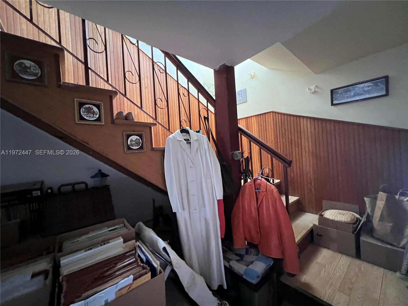 A staircase with wood paneling and railings features hanging coats and boxes in the entryway — 2278 SW 16th Ave, Miami FL 33145, MIAMI, FL