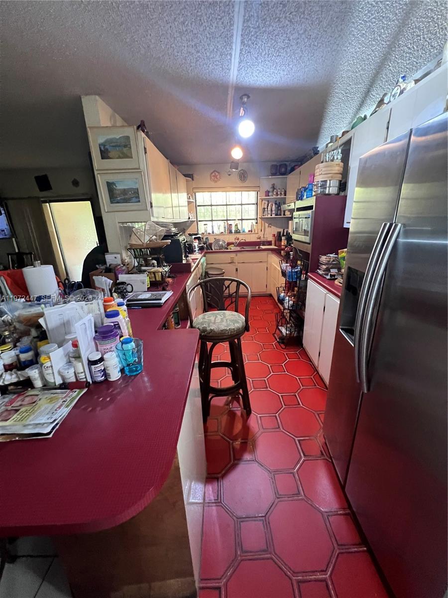 A kitchen features red hexagonal floor tiles, a red countertop, and a stainless steel refrigerator — 2278 SW 16th Ave, Miami FL 33145, MIAMI, FL