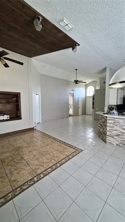 A living area with vaulted ceilings, tiled floors, a wood-paneled accent ceiling, and a kitchen counter — 2240 STONEHEDGE LOOP, KISSIMMEE, FL