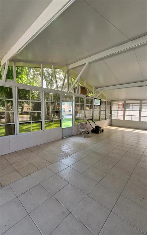 A spacious, tiled sunroom features large windows, a vaulted ceiling, and a glass door — 2240 STONEHEDGE LOOP, KISSIMMEE, FL