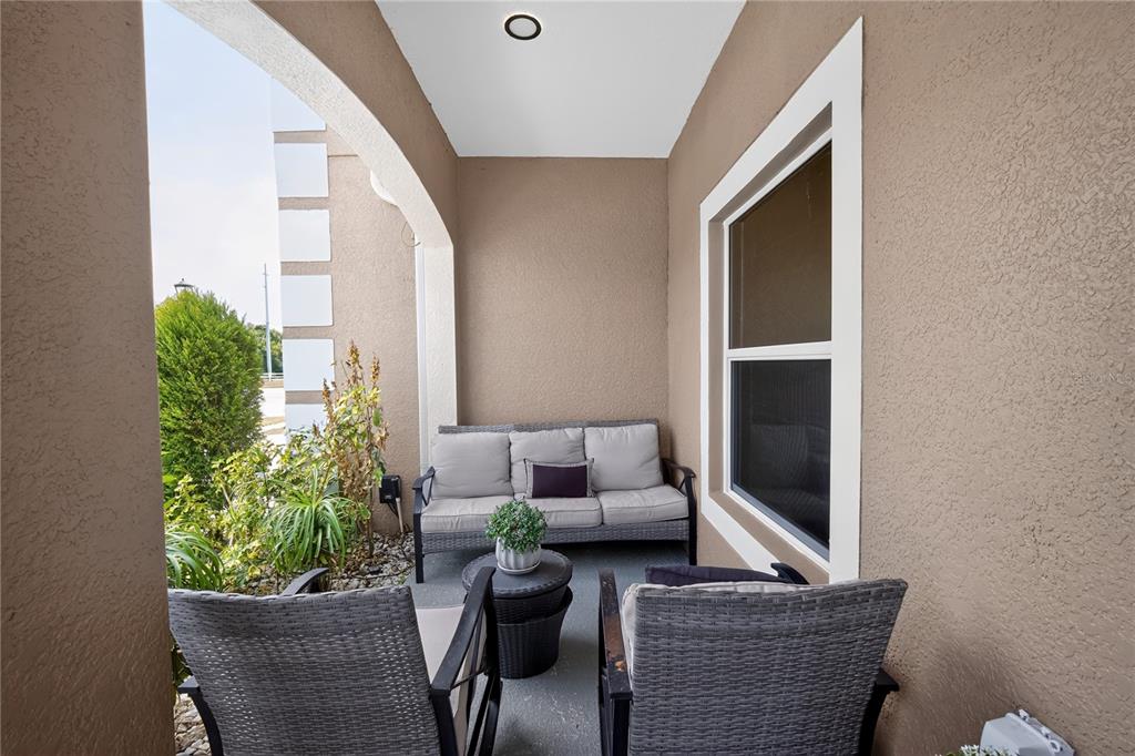 A covered patio features a gray sofa, two matching chairs, a small table, and plants — 12209 CITRUS LEAF DRIVE, GIBSONTON, FL