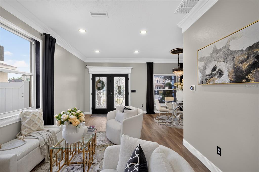 A bright living room features light gray walls, wood-look flooring, and a double front door — 12209 CITRUS LEAF DRIVE, GIBSONTON, FL