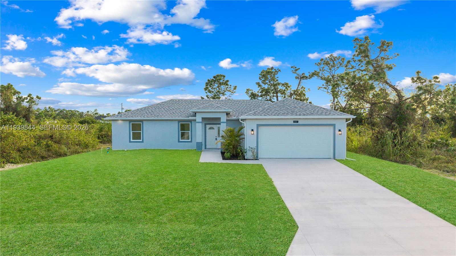 A single-story house with a light blue exterior, a two-car garage, and a concrete driveway — 3117 W 64th W, Lehigh Acres FL 33971, LEHIGH ACRES, FL