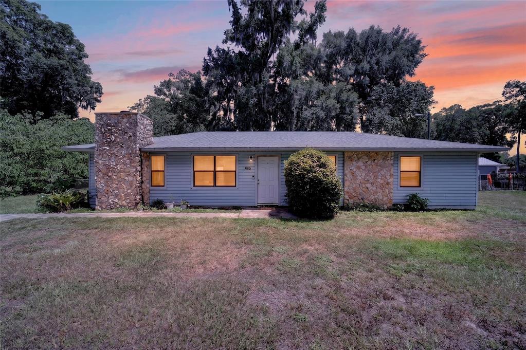 A single-story house with blue siding, a stone chimney, and a stone accent wall — 945 NW 64TH PLACE, OCALA, FL