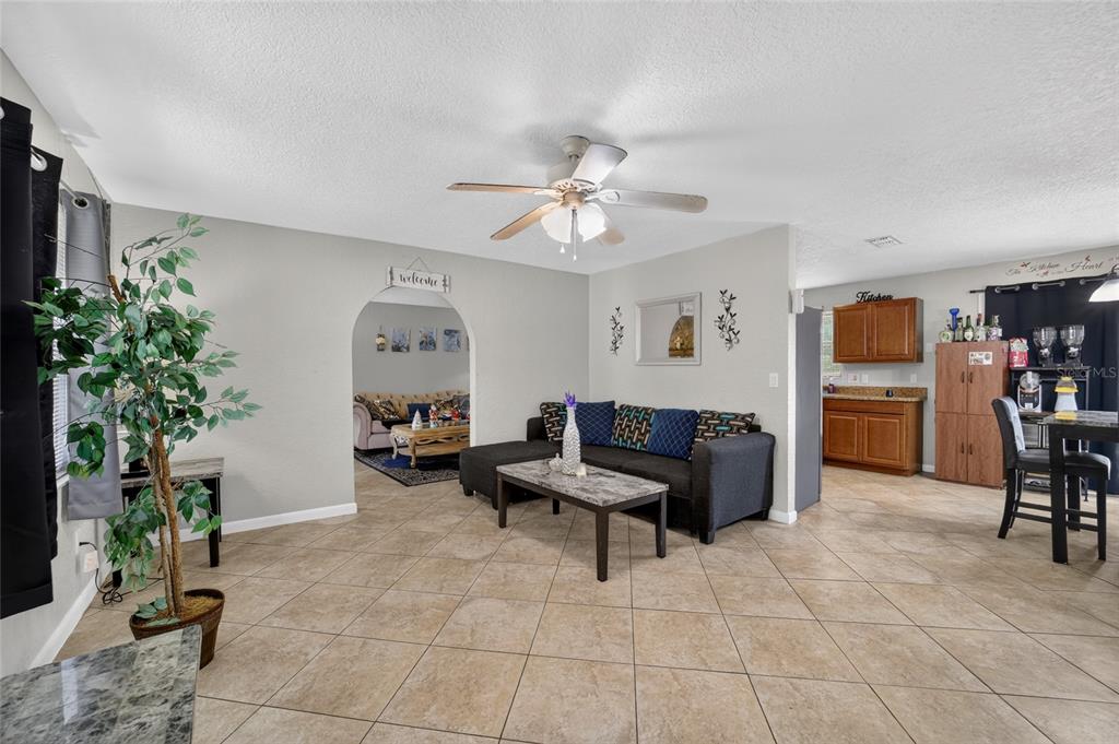 A living room with tile floors, a ceiling fan, and an arched entryway to another room — 945 NW 64TH PLACE, OCALA, FL