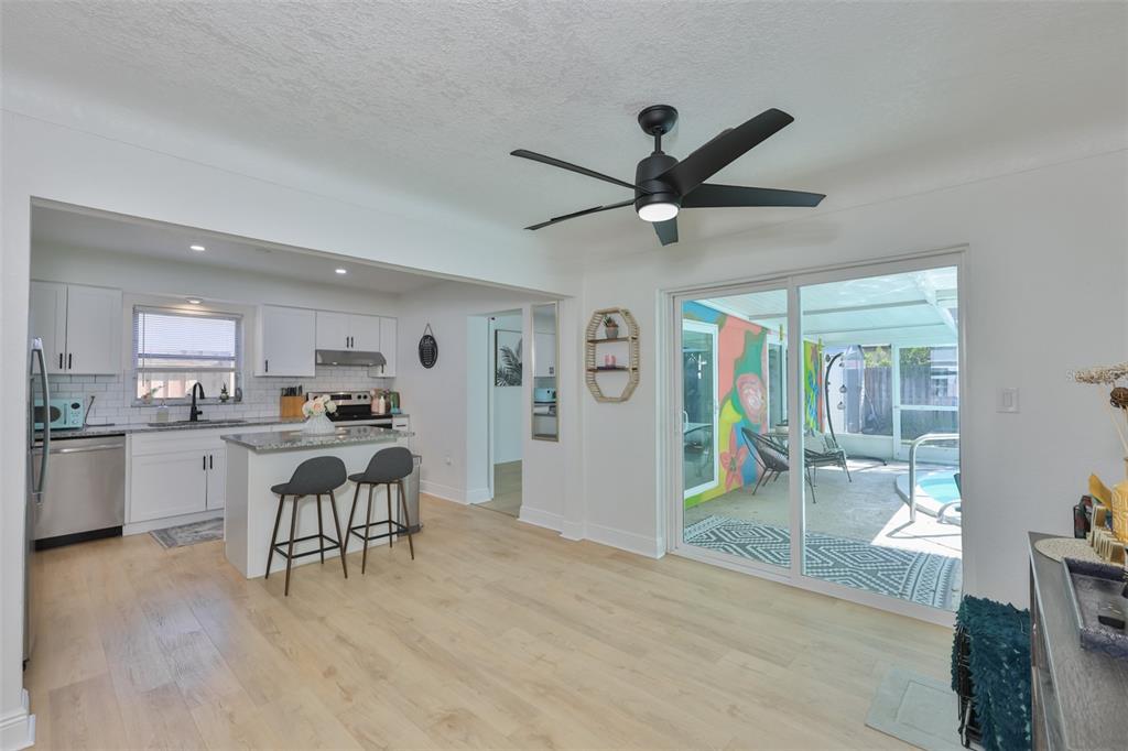 A kitchen with white cabinets and an island opens to a dining area with sliding doors — 8391 59TH LANE N, PINELLAS PARK, FL