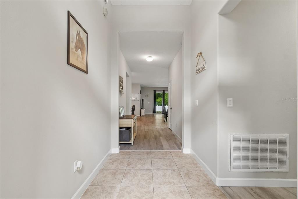 A tiled entryway leads into a hallway with wood-look flooring and an open living area — 12815 WHITE BLUFF ROAD, HUDSON, FL
