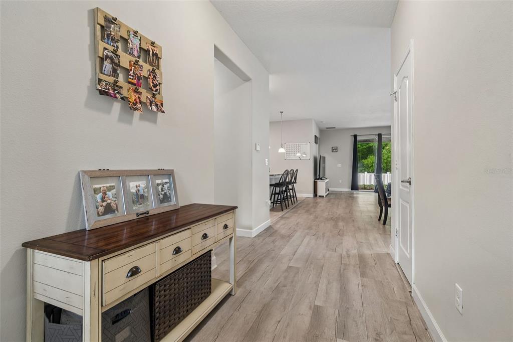 A hallway with wood-look flooring leads to an open-concept kitchen and living area — 12815 WHITE BLUFF ROAD, HUDSON, FL
