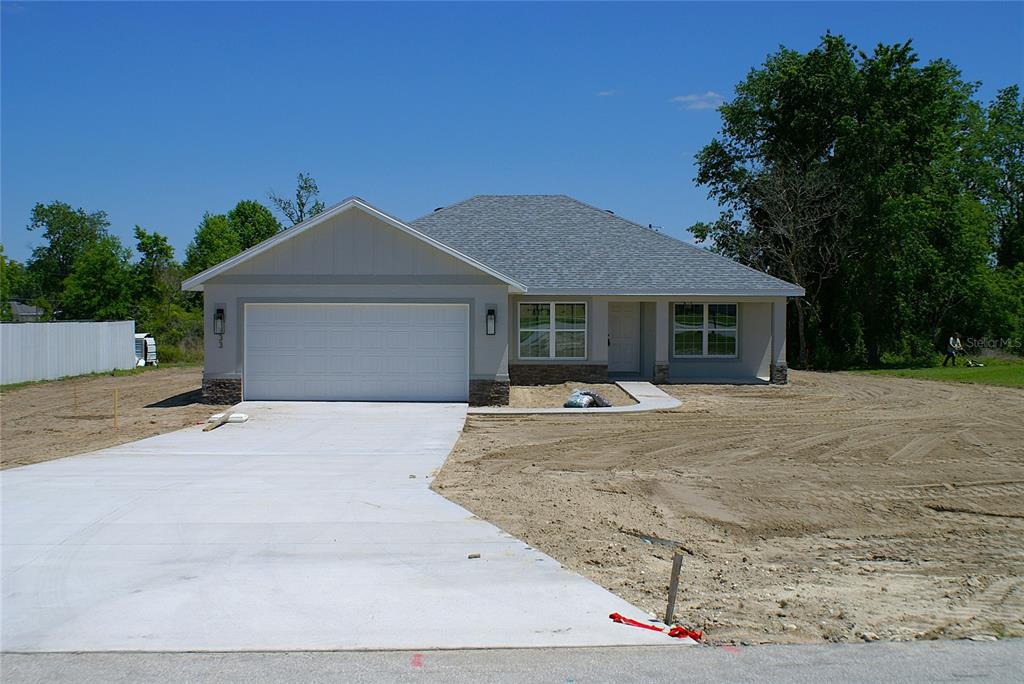 A newly constructed single-story house with a two-car garage and an unfinished dirt yard — 133 LARCH ROAD, OCALA, FL