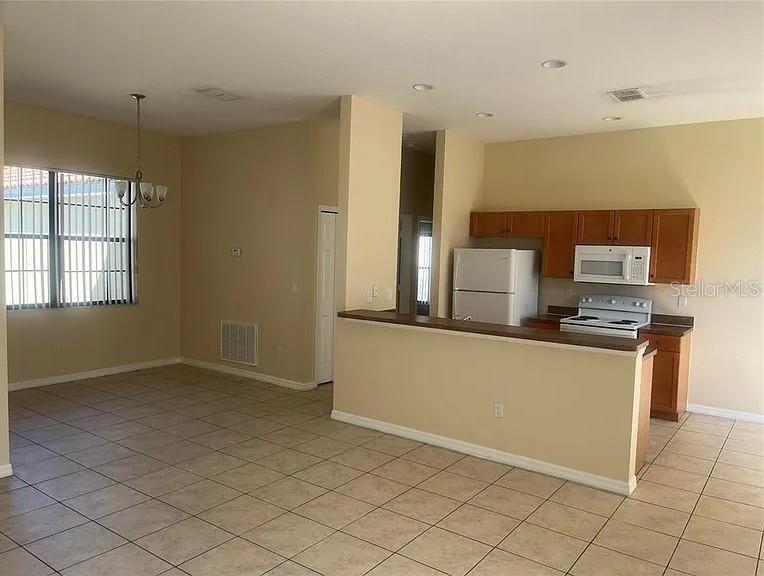A kitchen with wooden cabinets and a breakfast bar overlooks an adjacent dining area — 404 CINNAMON DRIVE, KISSIMMEE, FL