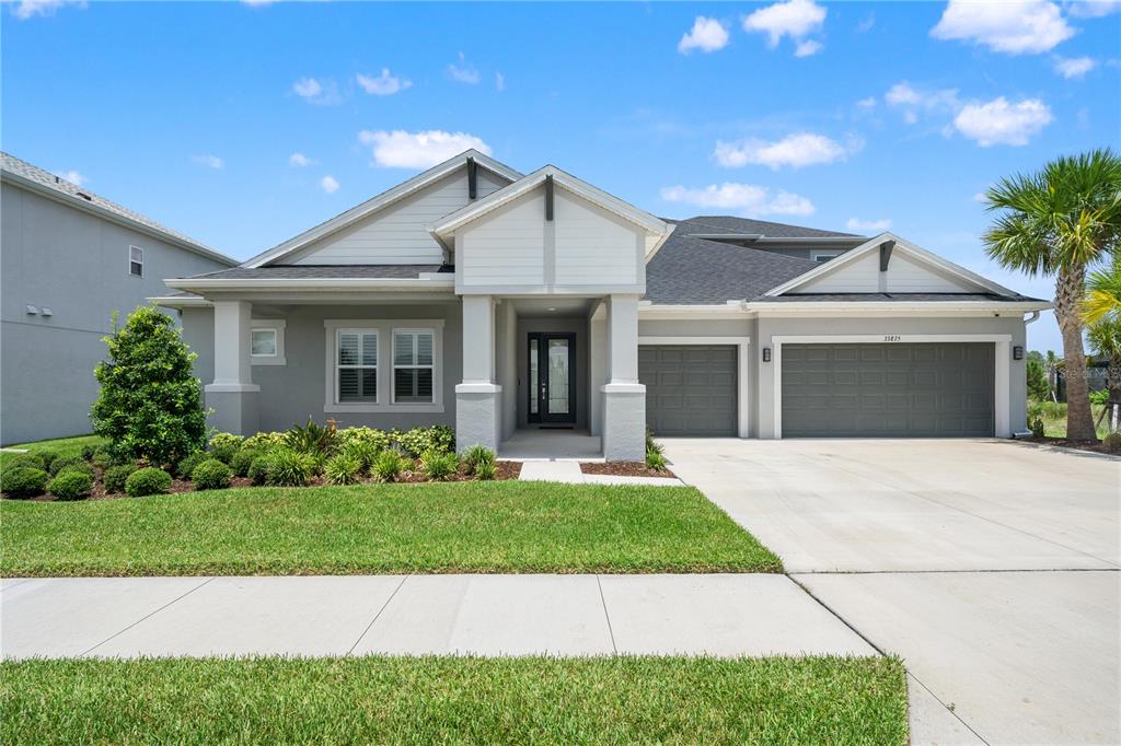A single-story house with a gray exterior, a two-car garage, and a front porch — 33875 CASTAWAY LOOP, WESLEY CHAPEL, FL