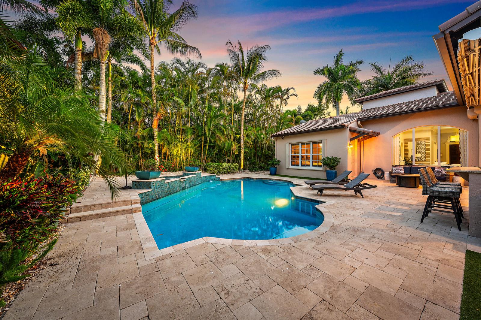 A backyard patio features a swimming pool, lounge chairs, and palm trees at sunset — 105 Segovia Way, Jupiter FL 33458, JUPITER, FL