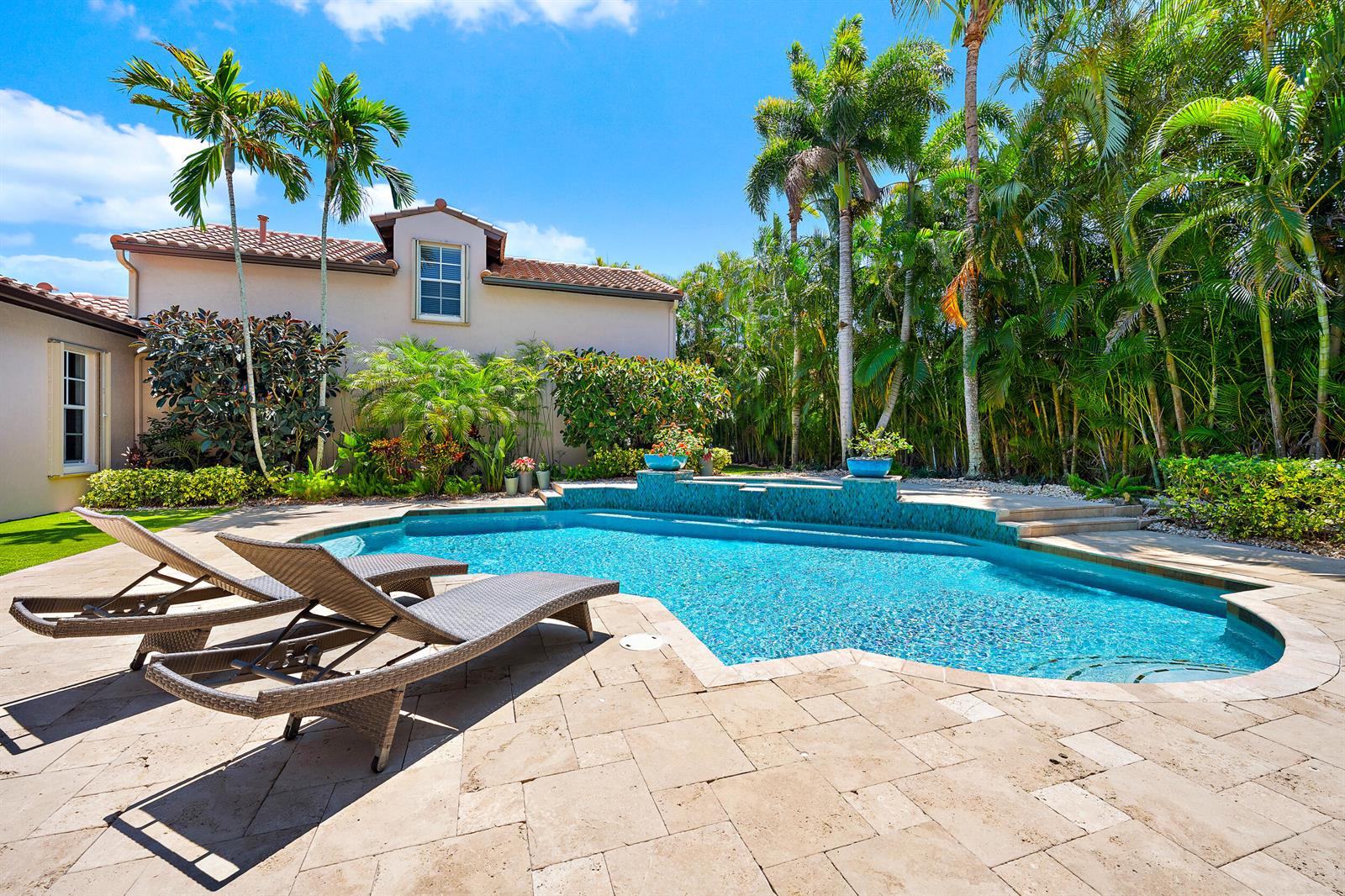 A backyard features a swimming pool with a tiled wall, lounge chairs, and palm trees — 105 Segovia Way, Jupiter FL 33458, JUPITER, FL