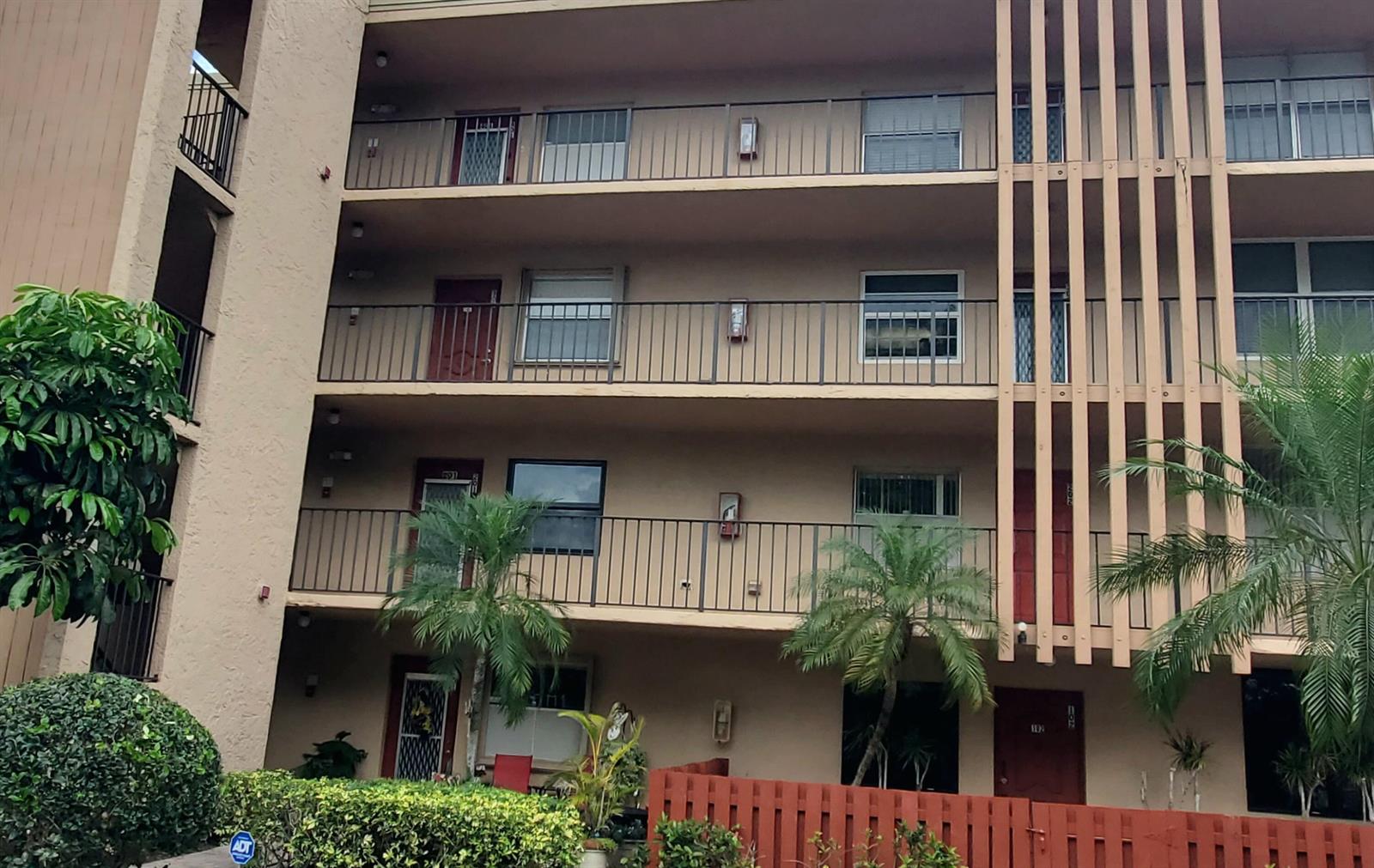 A multi-story apartment building exterior features balconies, sliding glass doors, and a red fence — 260 NW 76th Avenue # 201, Margate FL 33063, MARGATE, FL