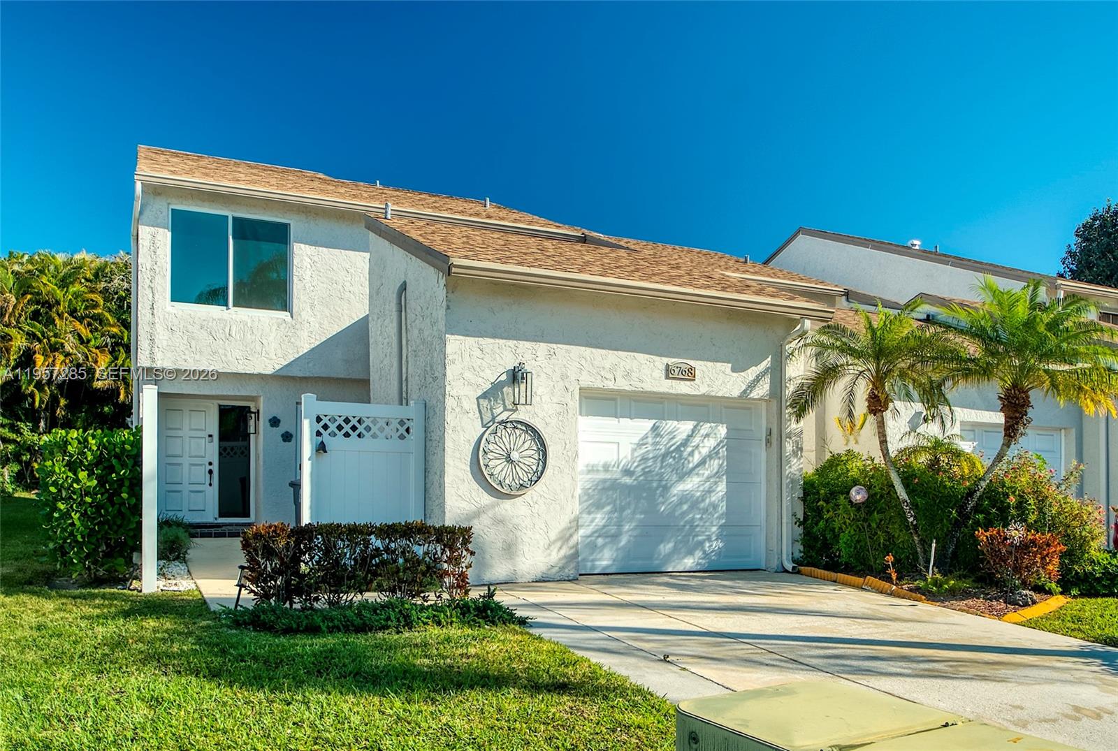 A two-story white stucco townhouse features a single-car garage and a small front courtyard — 6768 Canary Palm Cir, Boca Raton FL 33433, BOCA RATON, FL
