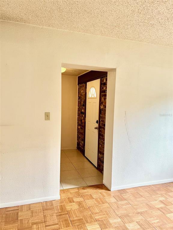 A view through a doorway shows a tiled entryway with a white door and brick wall — 718 BUCKMINSTER CIRCLE, ORLANDO, FL