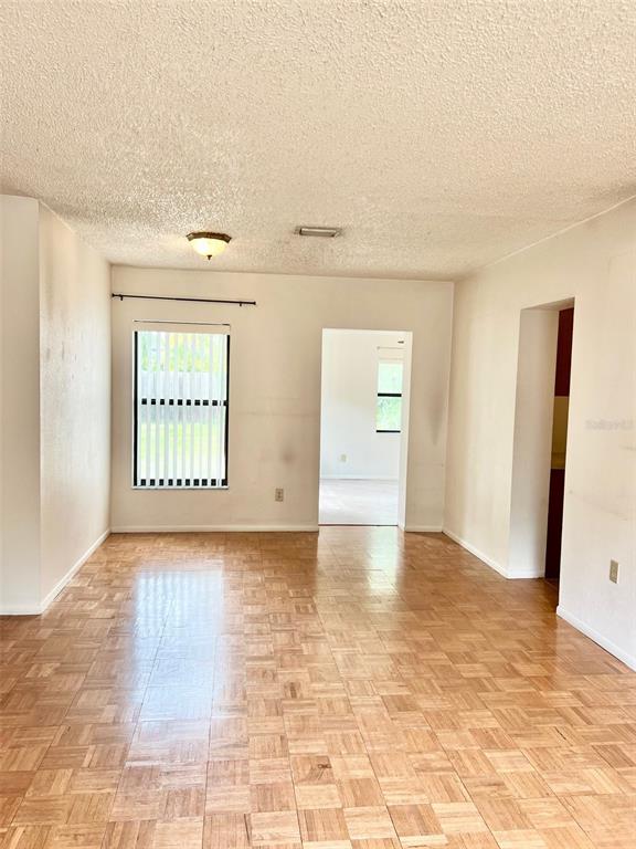 A room with parquet wood flooring, a window with vertical blinds, and a doorway — 718 BUCKMINSTER CIRCLE, ORLANDO, FL