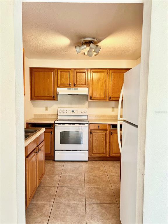 A kitchen features light wood cabinets, a white stove, and tile flooring — 718 BUCKMINSTER CIRCLE, ORLANDO, FL