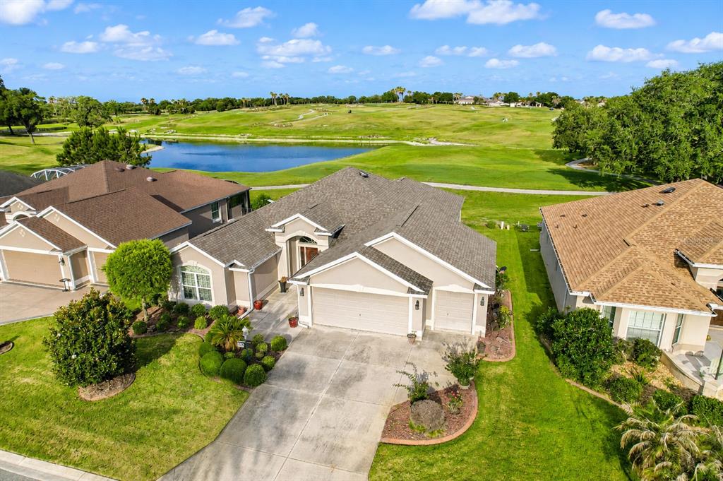An aerial view shows a suburban house with a garage, driveway, and golf course backdrop — 2696 MIDLAND TERRACE, THE VILLAGES, FL