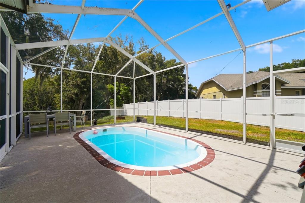 An open-concept living room with wood floors, a ceiling fan, and an adjacent white kitchen — 448 LAKE HARRIS DRIVE, LAKELAND, FL