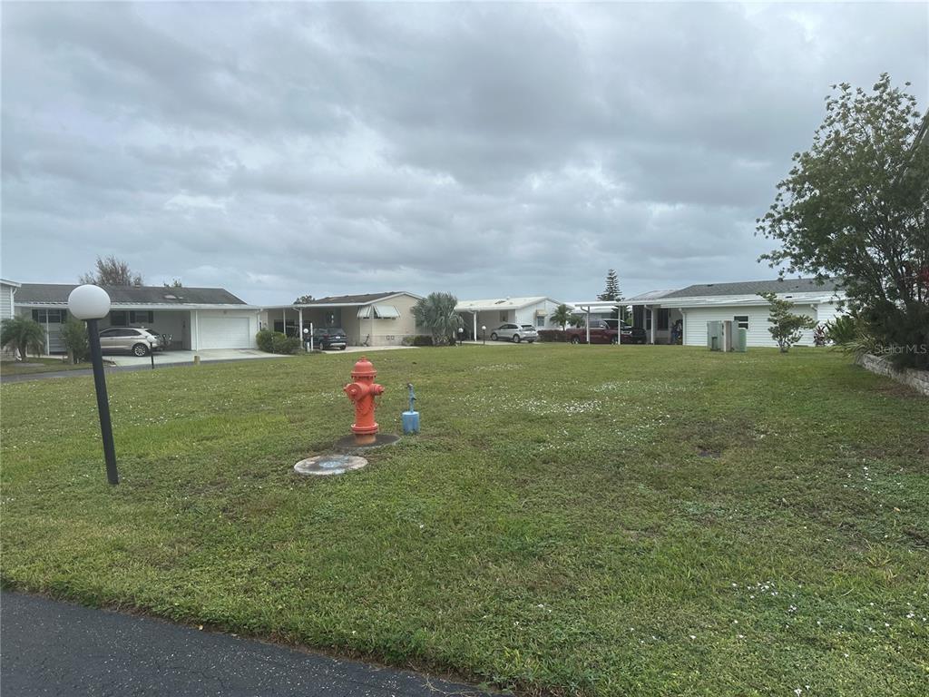 A vacant grassy lot features a fire hydrant and utility access in a residential neighborhood — 698 SANDWEDGE DRIVE, FROSTPROOF, FL