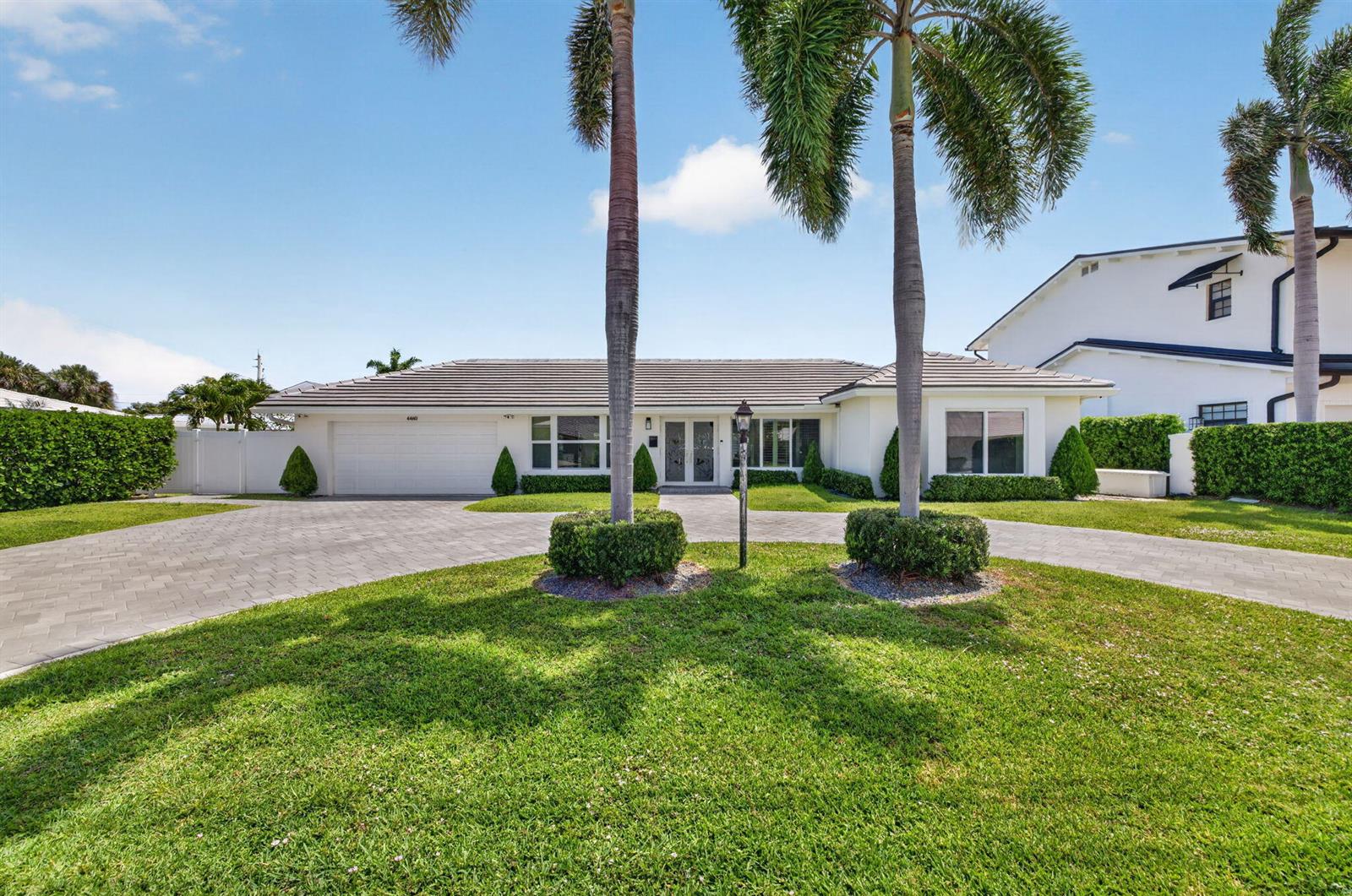 A single-story house with a paved driveway, palm trees, and a white exterior — 4460 NE 26th Avenue, Lighthouse Point FL 33064, LIGHTHOUSE POINT, FL