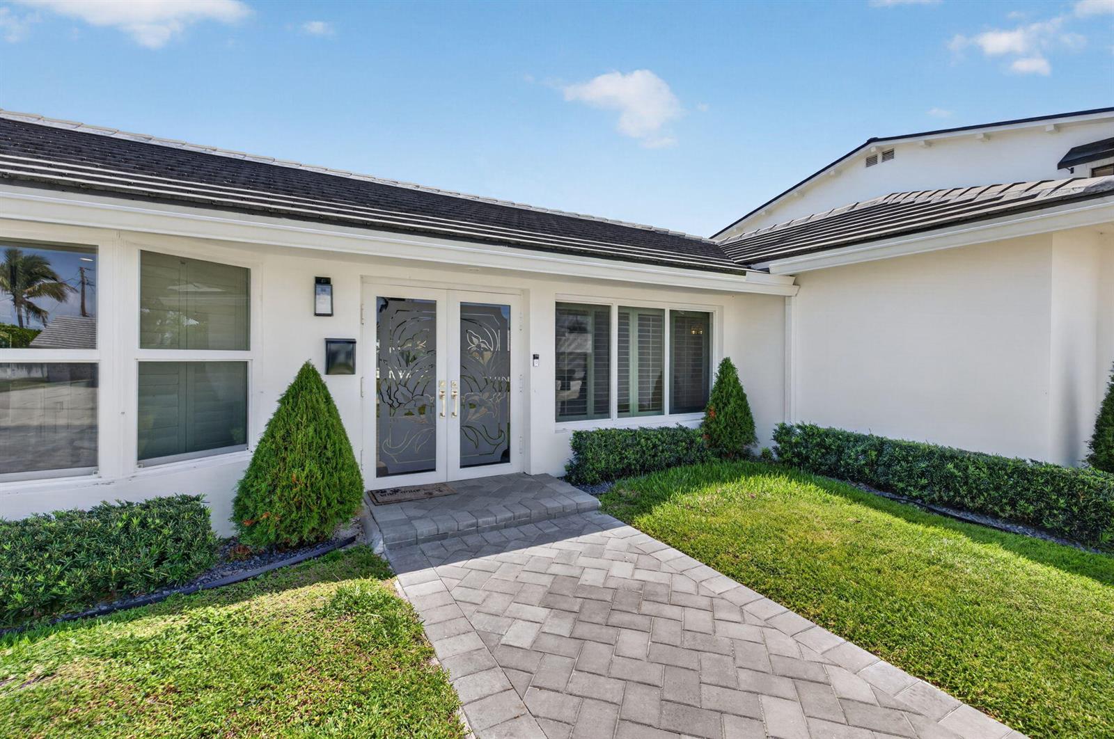 A white house exterior features a paved walkway leading to double glass front doors — 4460 NE 26th Avenue, Lighthouse Point FL 33064, LIGHTHOUSE POINT, FL