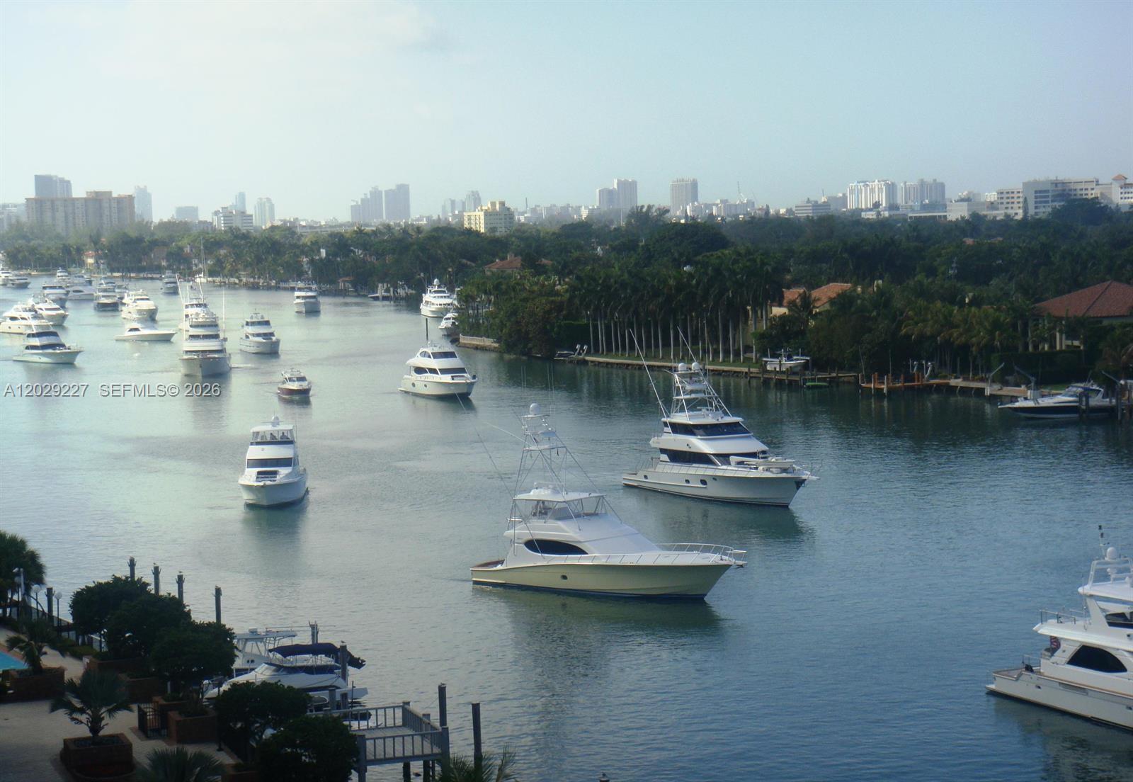 An elevated view shows a waterfront patio with a flagpole and lush landscaping — 5700 Collins Ave # 8K, Miami Beach FL 33140, MIAMI BEACH, FL