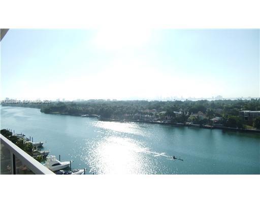 An aerial view shows a swimming pool, lounge chairs, and boats docked along a waterway — 5700 Collins Ave # 8K, Miami Beach FL 33140, MIAMI BEACH, FL