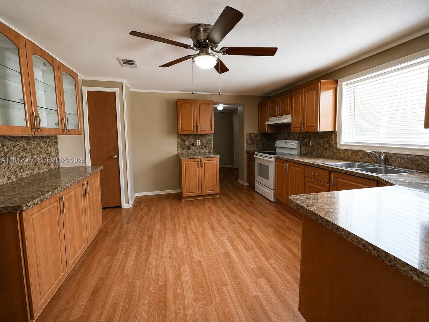 A kitchen features wood cabinets, laminate countertops, a ceiling fan, and light wood flooring — 19800 SW 180th Ave Lot 583, Miami FL 33187, MIAMI, FL