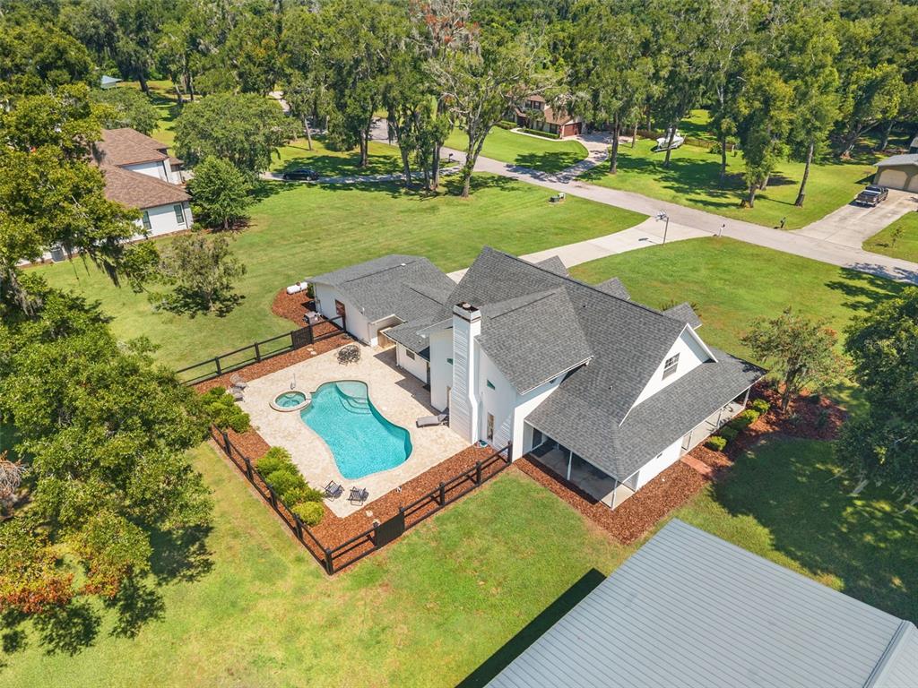 An aerial view shows a white house with a dark roof, pool, and fenced yard — 37714 FAIRFIELD LANE, DADE CITY, FL