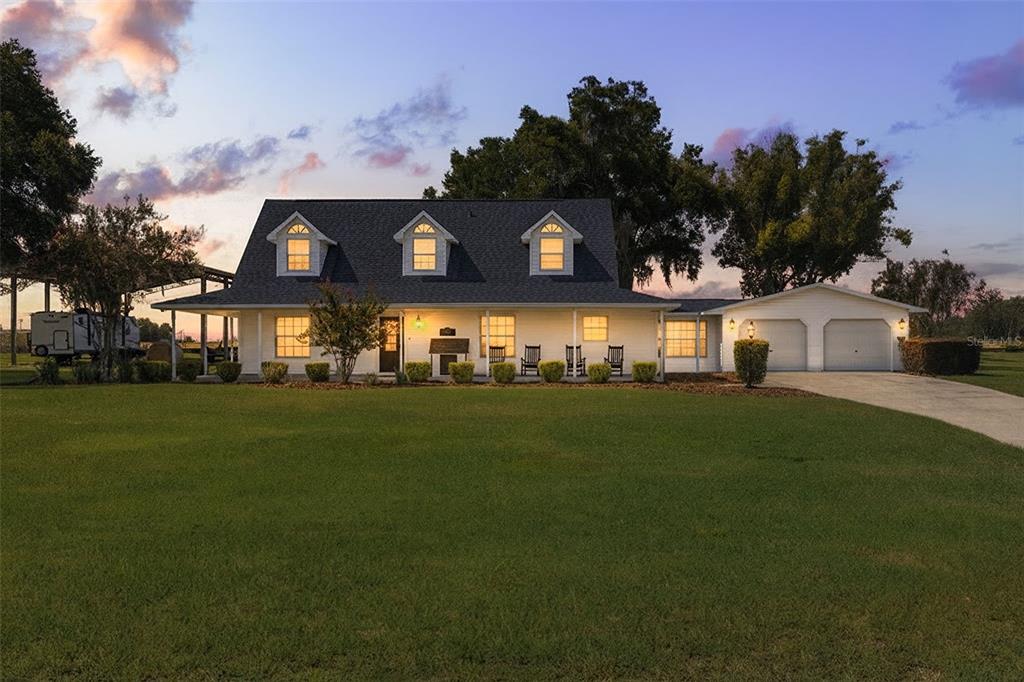 A two-story white house with a covered porch, dormer windows, and an attached garage — 37714 FAIRFIELD LANE, DADE CITY, FL