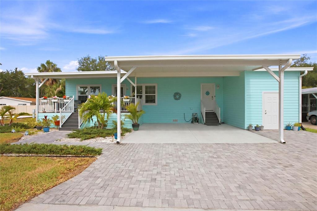 A light blue manufactured home features a paved driveway, a carport, and a front deck — 4378 MANATEE LOOP UNIT 19A, PUNTA GORDA, FL