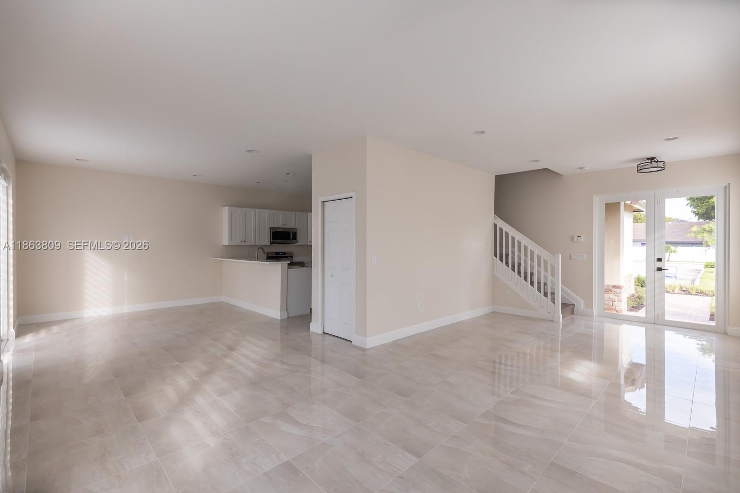 An open-concept living area features light-colored tile flooring, a kitchen, and a staircase — 5400 NW 57th Ct, Tamarac FL 33319, TAMARAC, FL