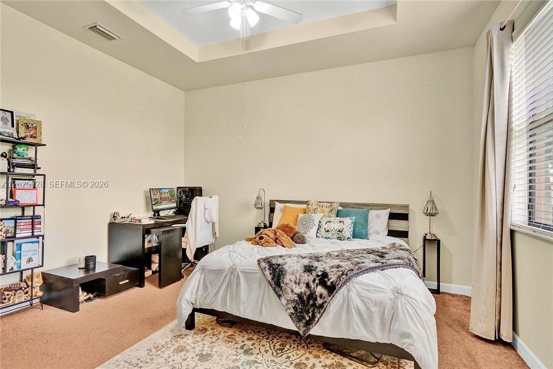 A bedroom features a bed with decorative pillows, a desk, and a tall shelving unit — 821 E Village Cir # 821, Davie FL 33325, DAVIE, FL