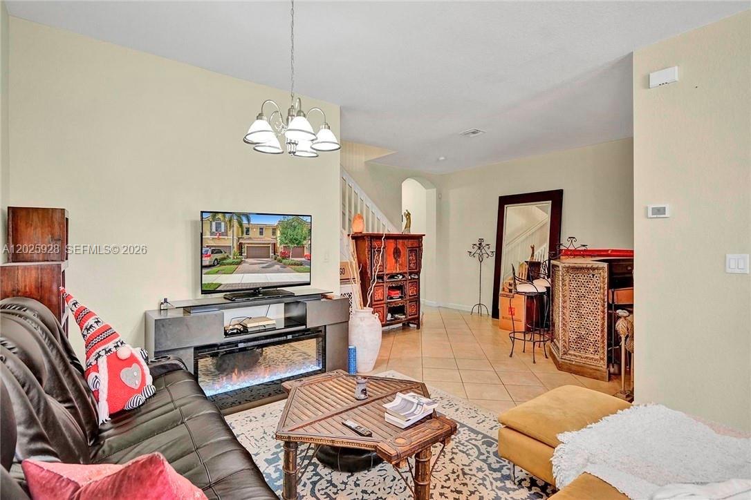 A living room features a fireplace console, a television, tile flooring, and a staircase — 821 E Village Cir # 821, Davie FL 33325, DAVIE, FL