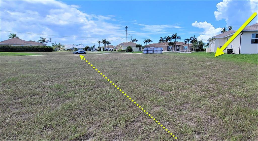 A vacant, grassy residential lot is shown with yellow arrows indicating the property boundaries — 3690 WHIPPOORWILL BOULEVARD, PUNTA GORDA, FL