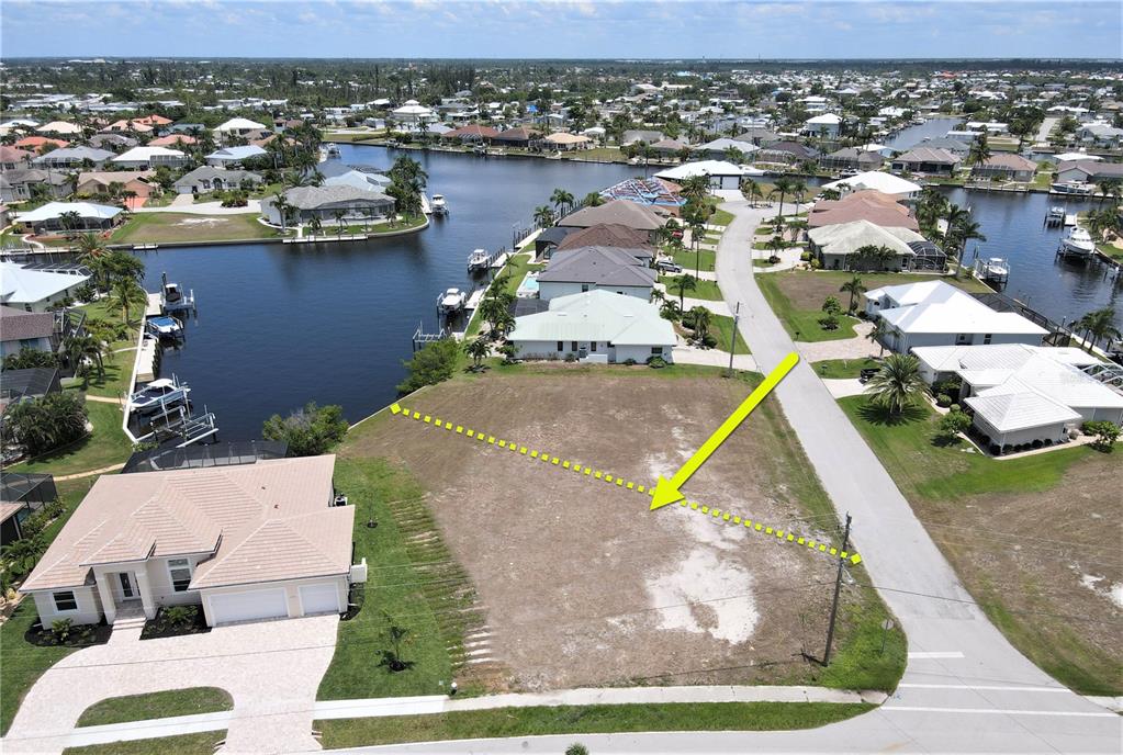 An aerial view shows a vacant waterfront residential lot marked with a yellow arrow — 3690 WHIPPOORWILL BOULEVARD, PUNTA GORDA, FL