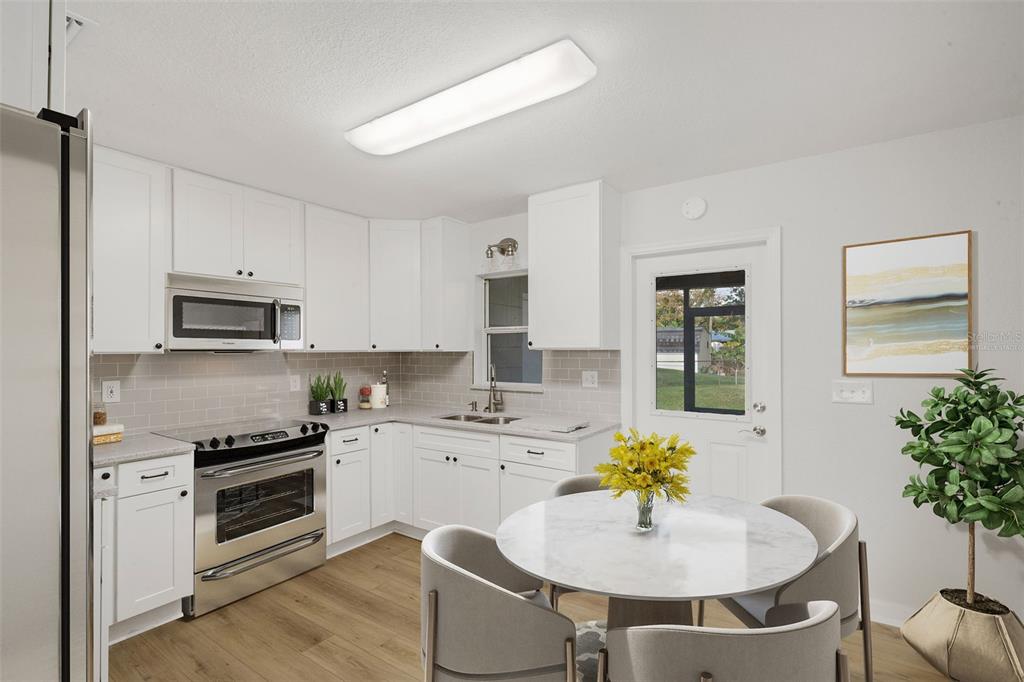 A kitchen with white cabinets, stainless steel appliances, and a small dining area — 2716 HARDIN COMBEE ROAD, LAKELAND, FL