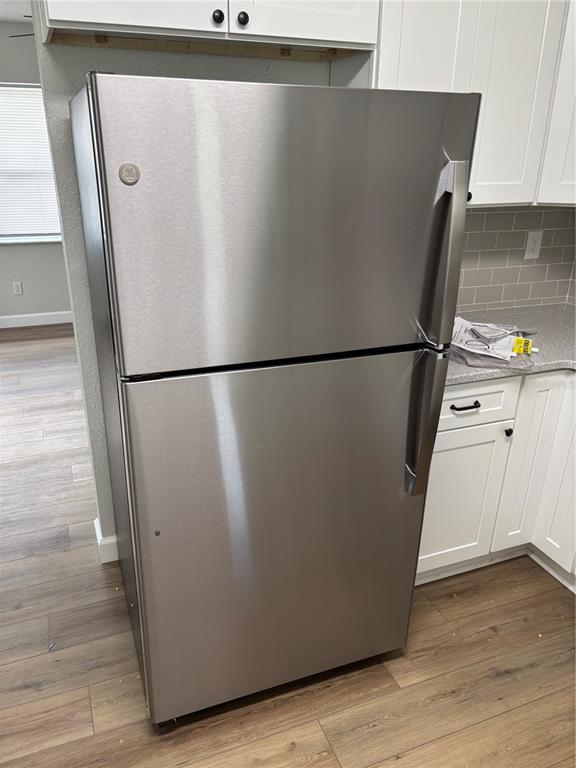 A stainless steel top-freezer refrigerator stands in a kitchen with white cabinets and wood flooring — 2716 HARDIN COMBEE ROAD, LAKELAND, FL