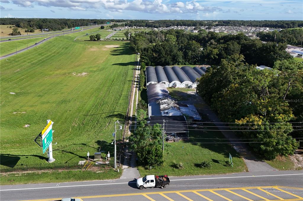 An aerial view shows a rural property with greenhouses, a small building, and a highway — 3243 W KELLY PARK ROAD, APOPKA, FL