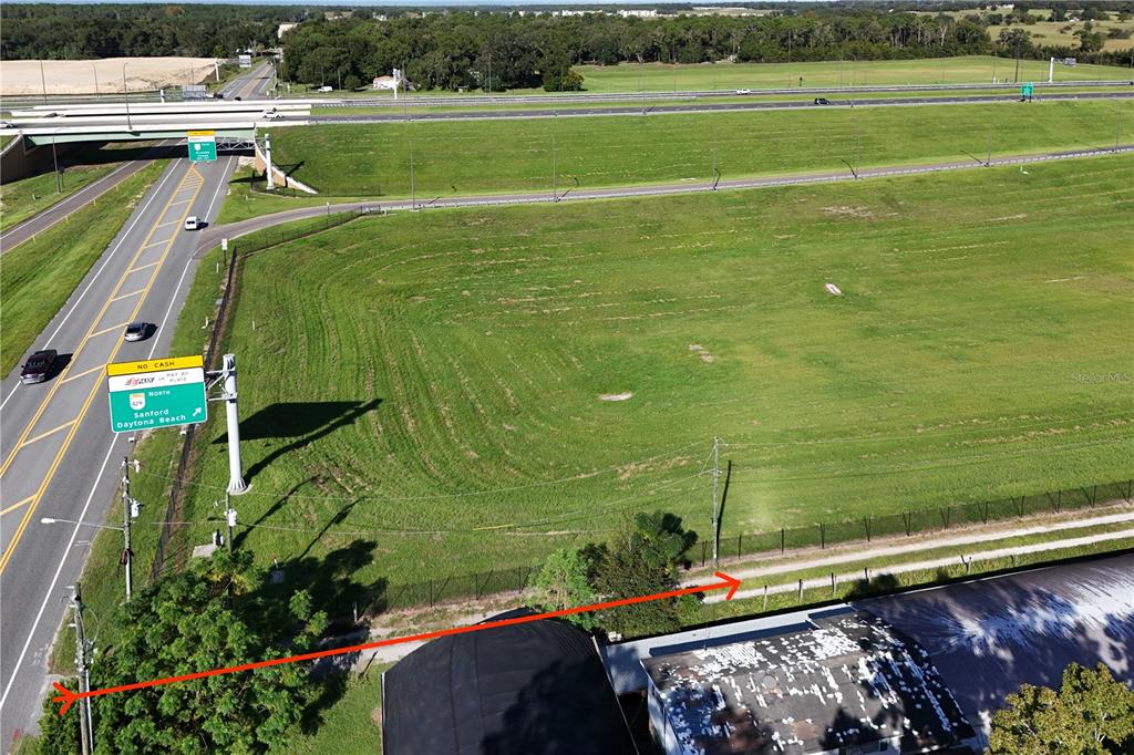 An aerial view shows a grassy vacant lot adjacent to a highway and an overpass — 3243 W KELLY PARK ROAD, APOPKA, FL